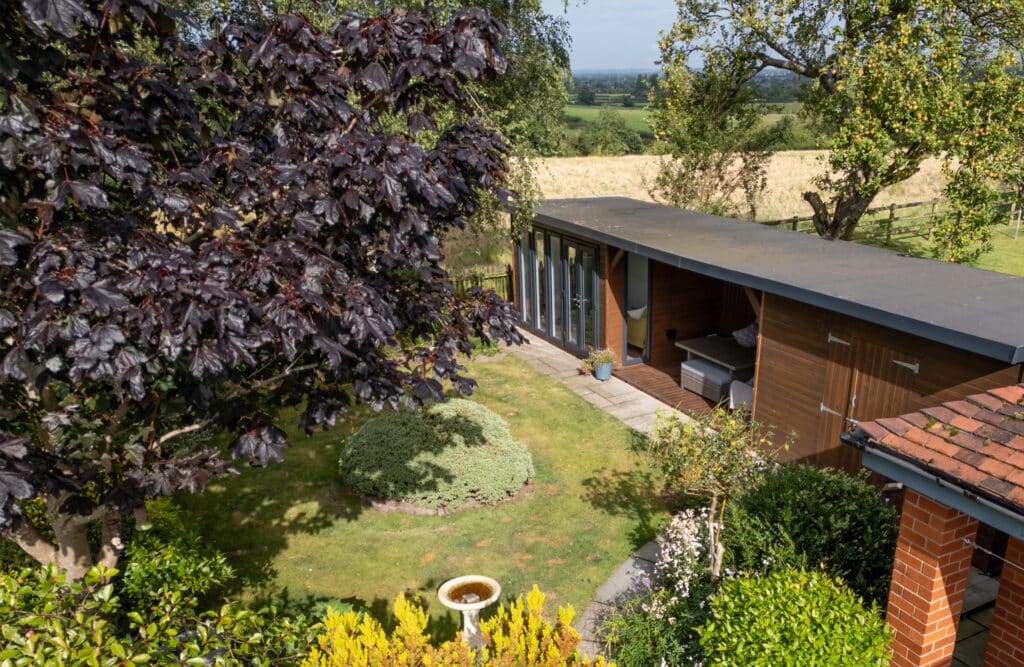 bespoke garden room by roundpeg outdoor buildings looking out over the hills of derbyshire surrounded by foliage